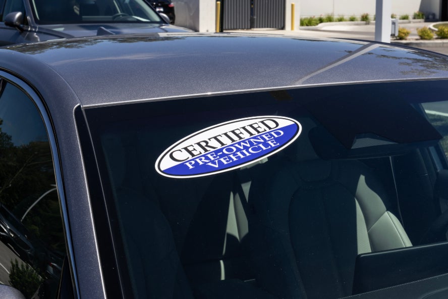 A car with a certified pre-owned vehicle sticker on the windshield.