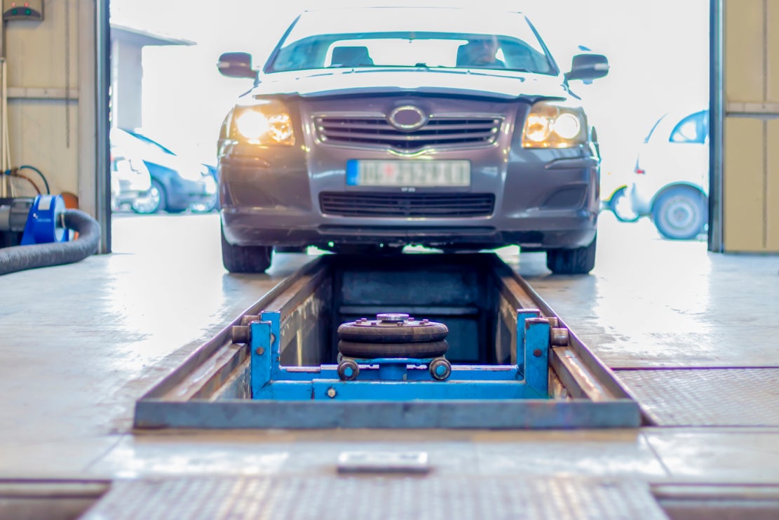 A blue car being moved into an inspection lane at a vehicle service center.