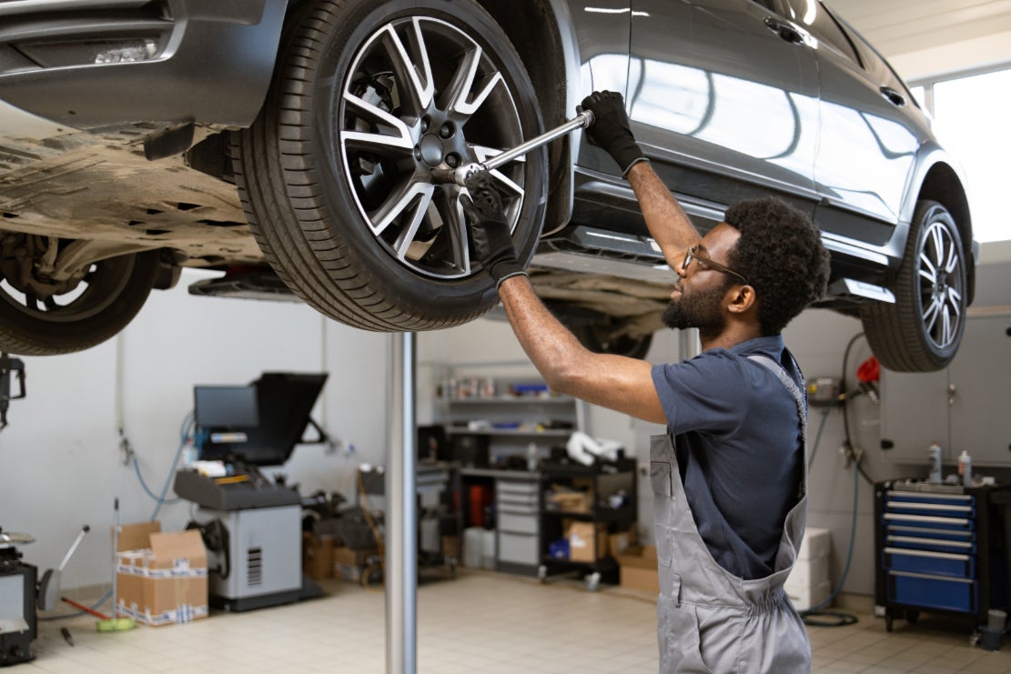 A mechanic working on a vehicle on a raised platform.